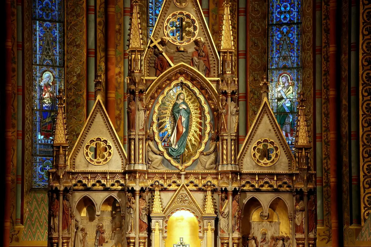 The gilded Gothic altar of Matthias Church with a painted Virgin in an oval frame between blue stained-glass windows