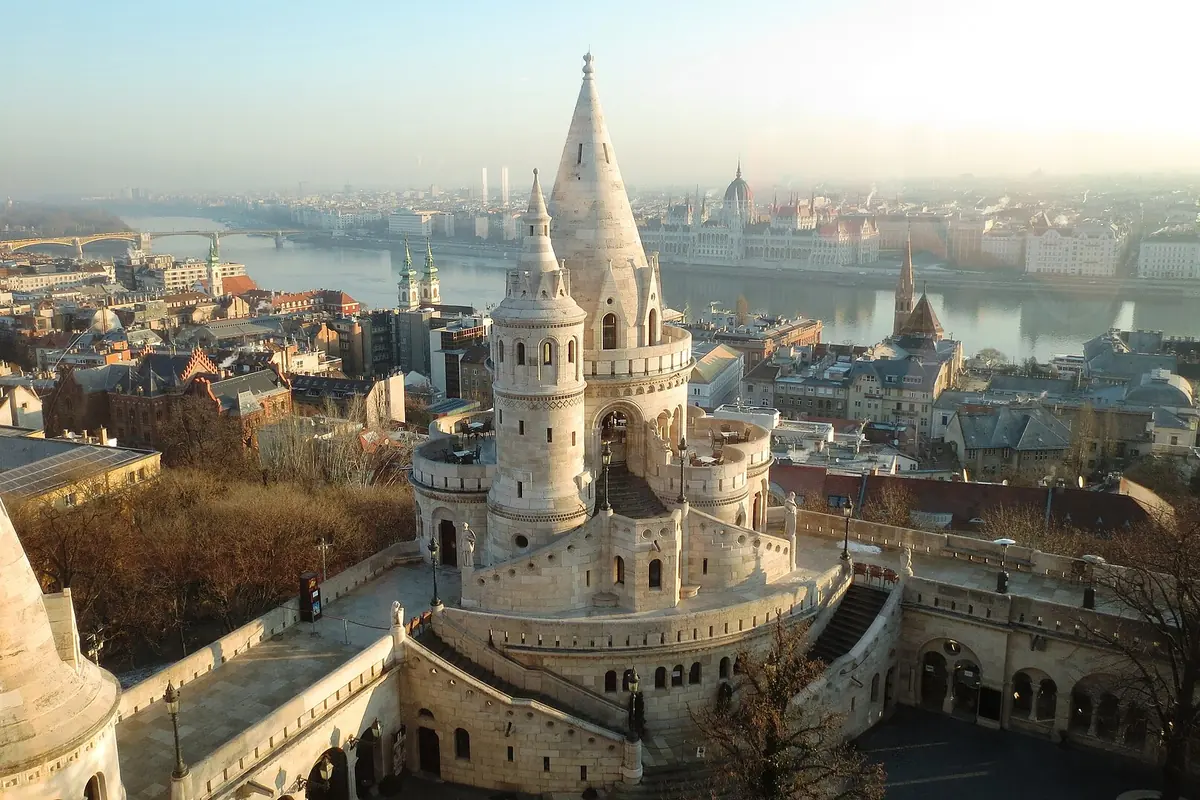 Rooftops of Buda with the white conical towers of the Fisherman's Bastion in the foreground and the Danube winding away behind